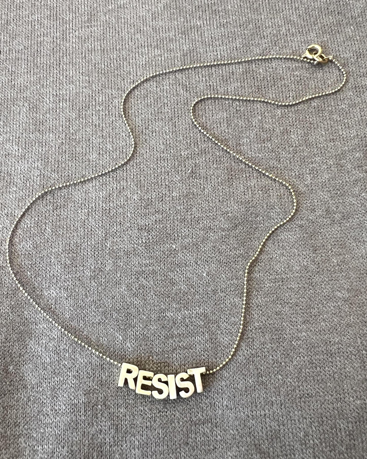 Sara Sela Brass RESIST Lettered Charm Necklace