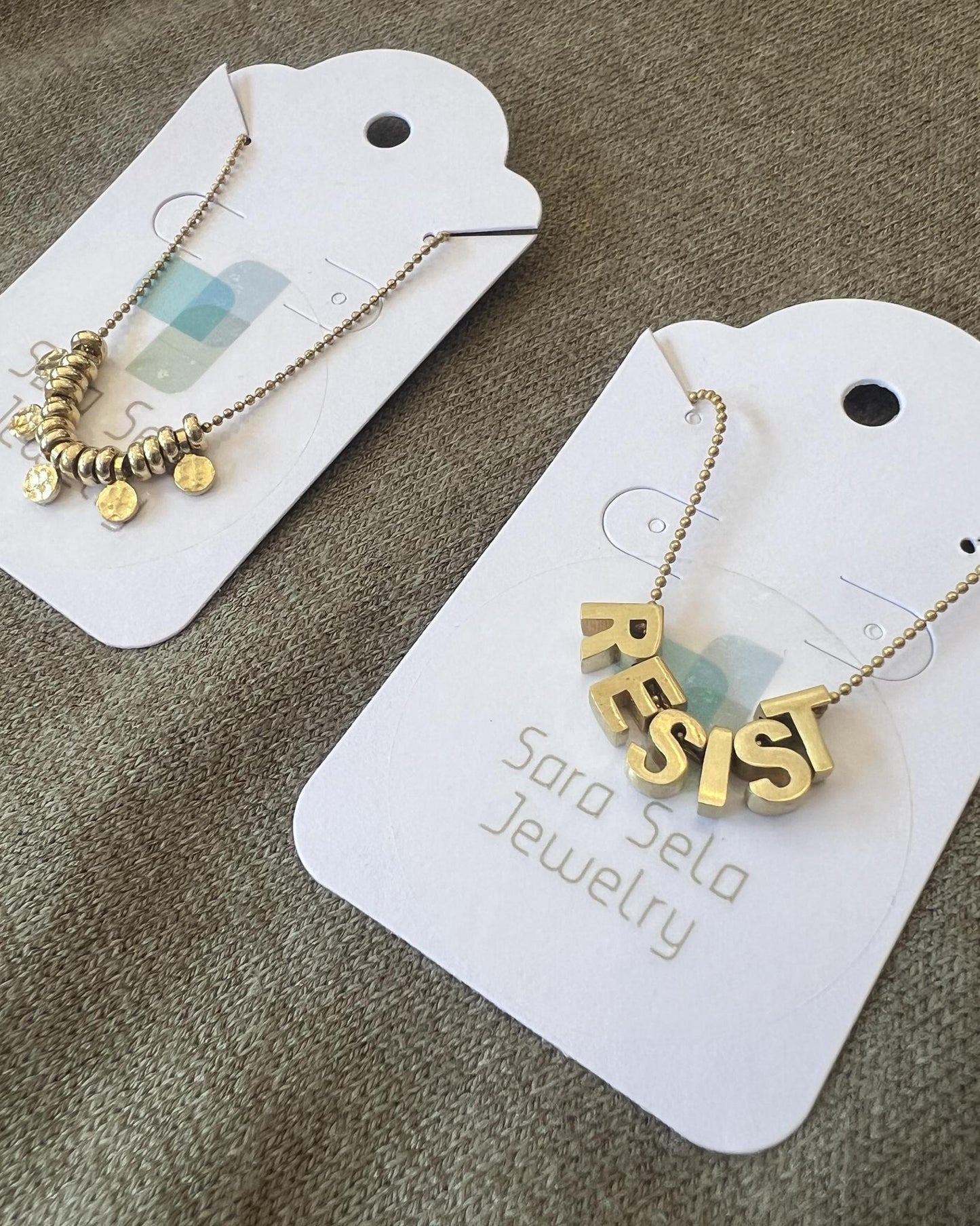 Sara Sela Brass RESIST Lettered Charm Necklace