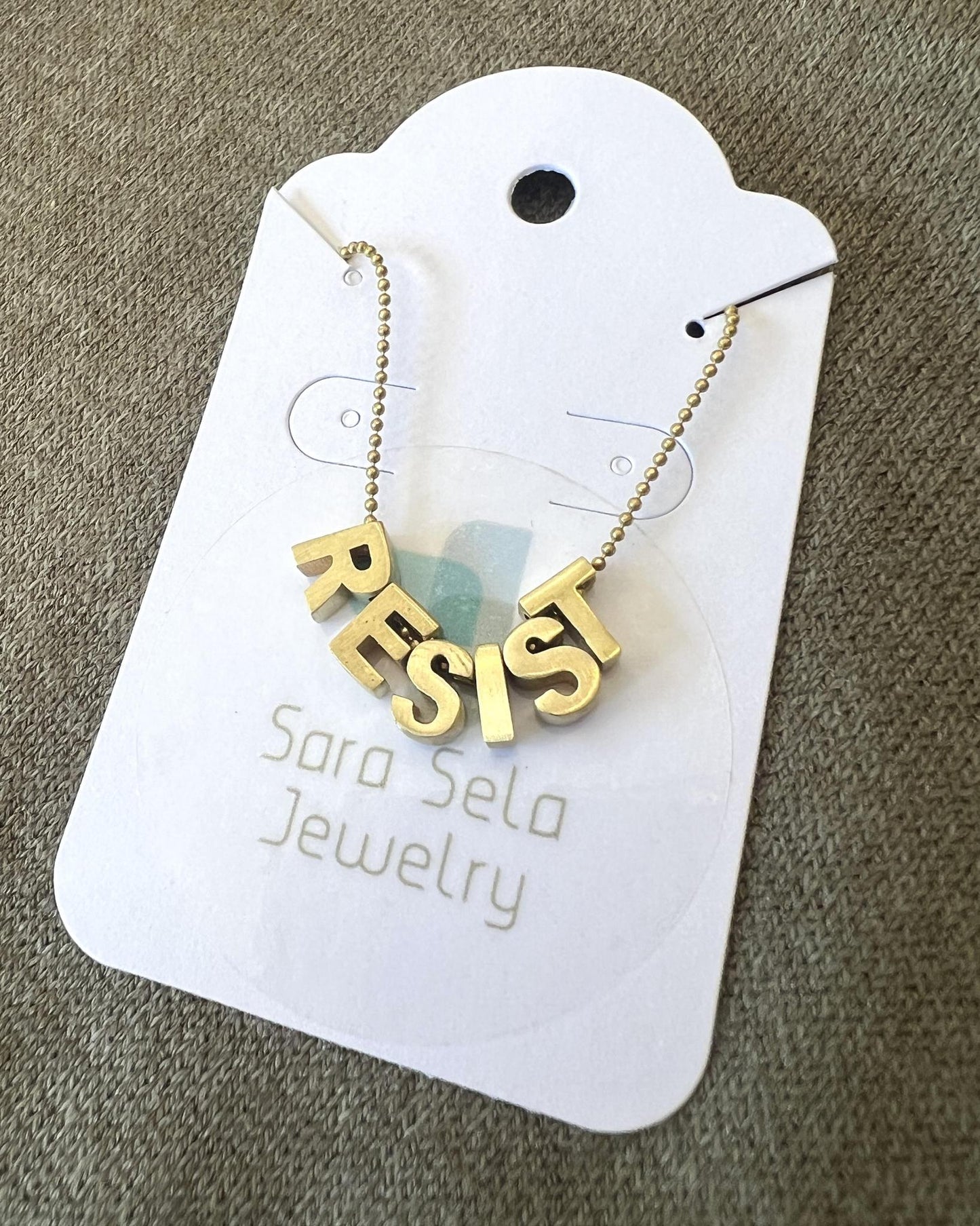 Sara Sela Brass RESIST Lettered Charm Necklace