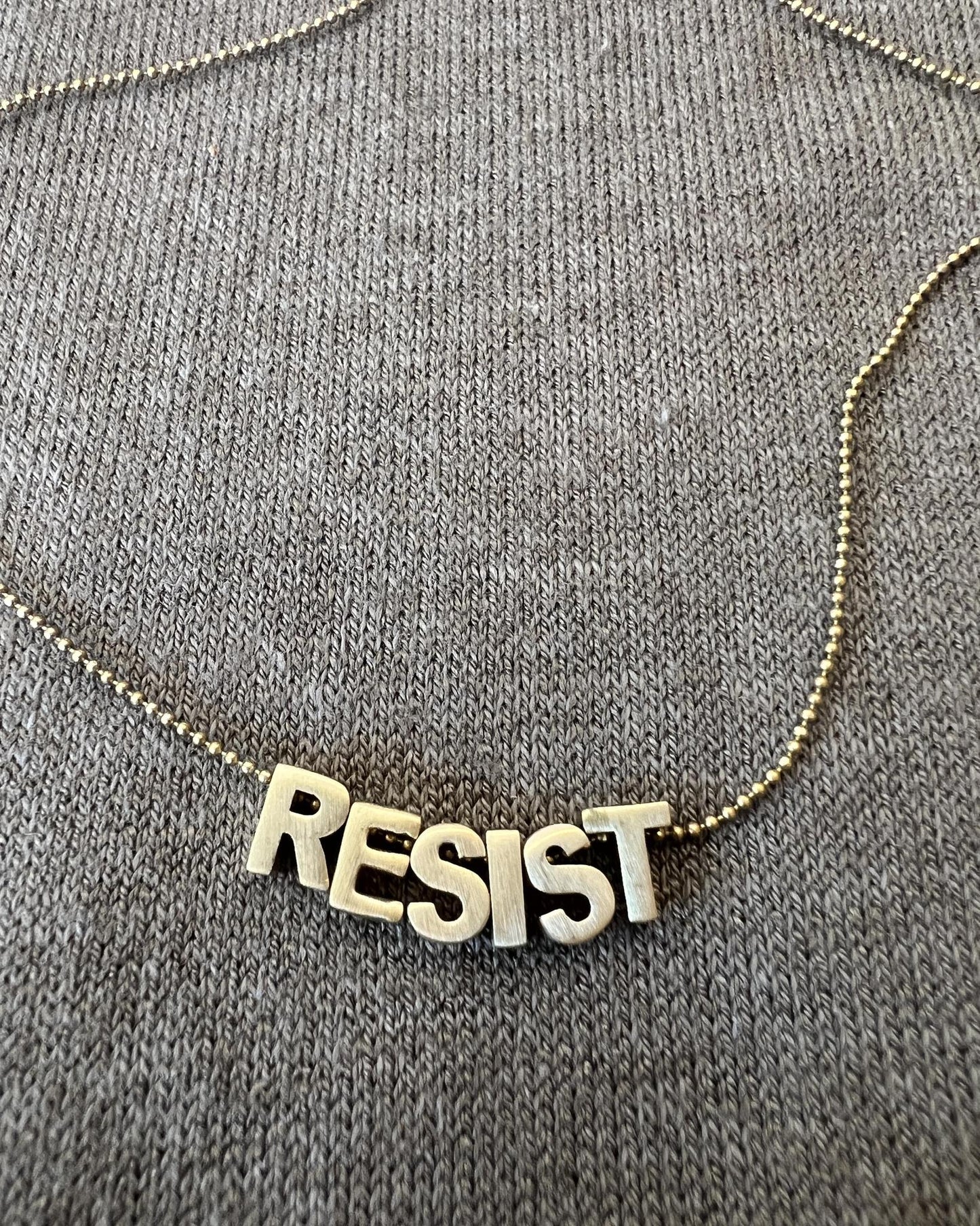 Sara Sela Brass RESIST Lettered Charm Necklace